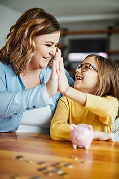 Woman teaching her daughter about financial planning with a piggy bank