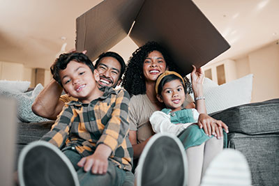 Happy family of four smiling on the couch in their new home