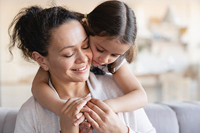 Young daughter embracing her smiling mother