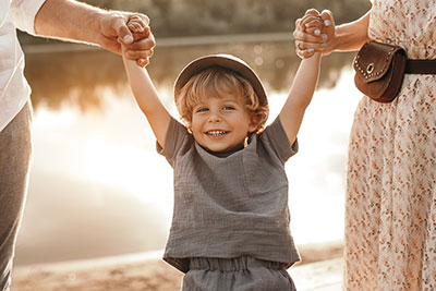 Parents holding their smiling toddler by the arms