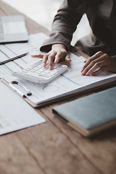 Man using a calculator and charts to figure out how much life insurance he needs