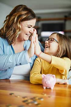 Mom and daughter practicing saving money with a piggy bank